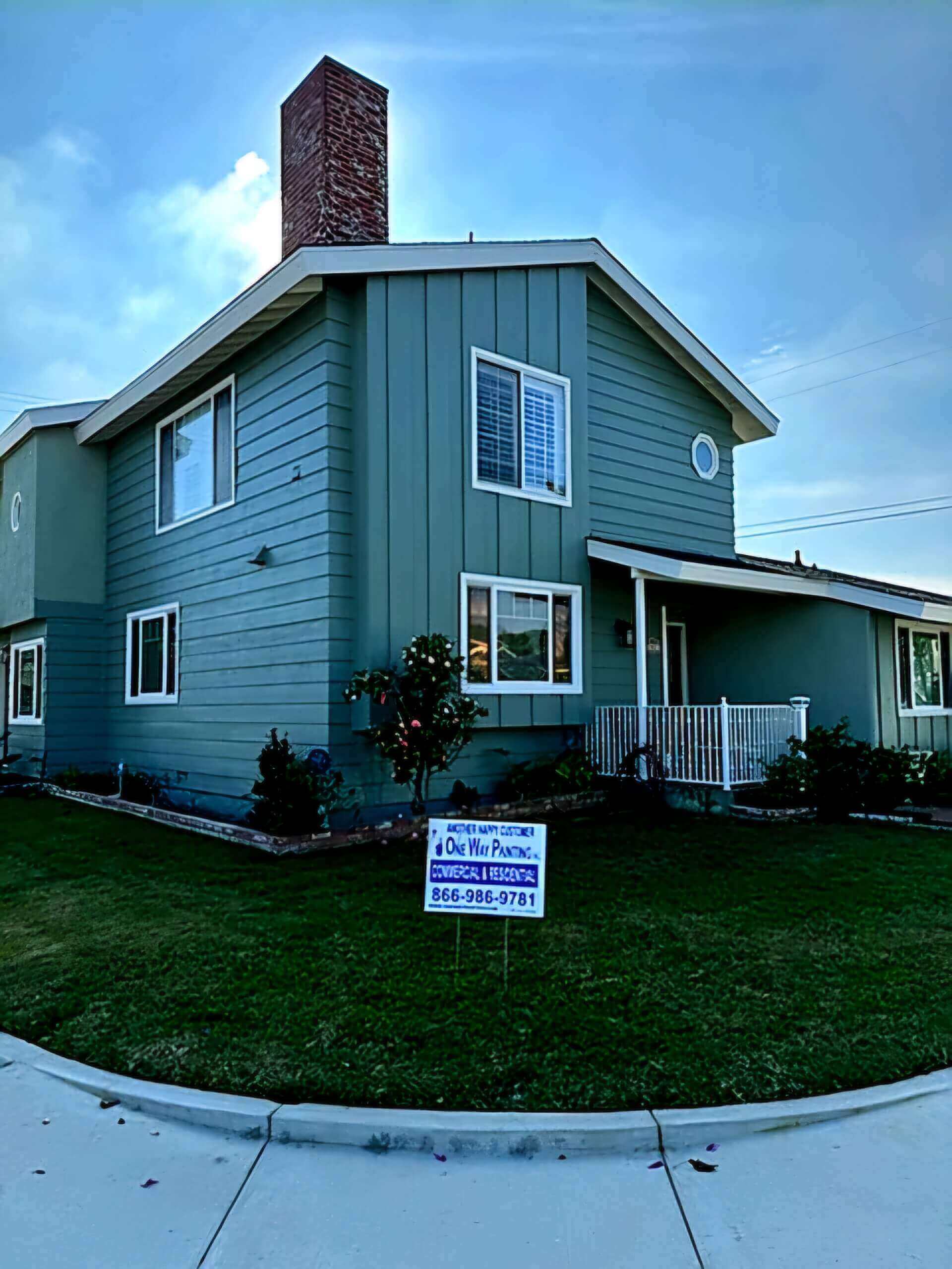 Two-story house in Costa Mesa after painting, maintaining the light turquoise color on siding and white trim.