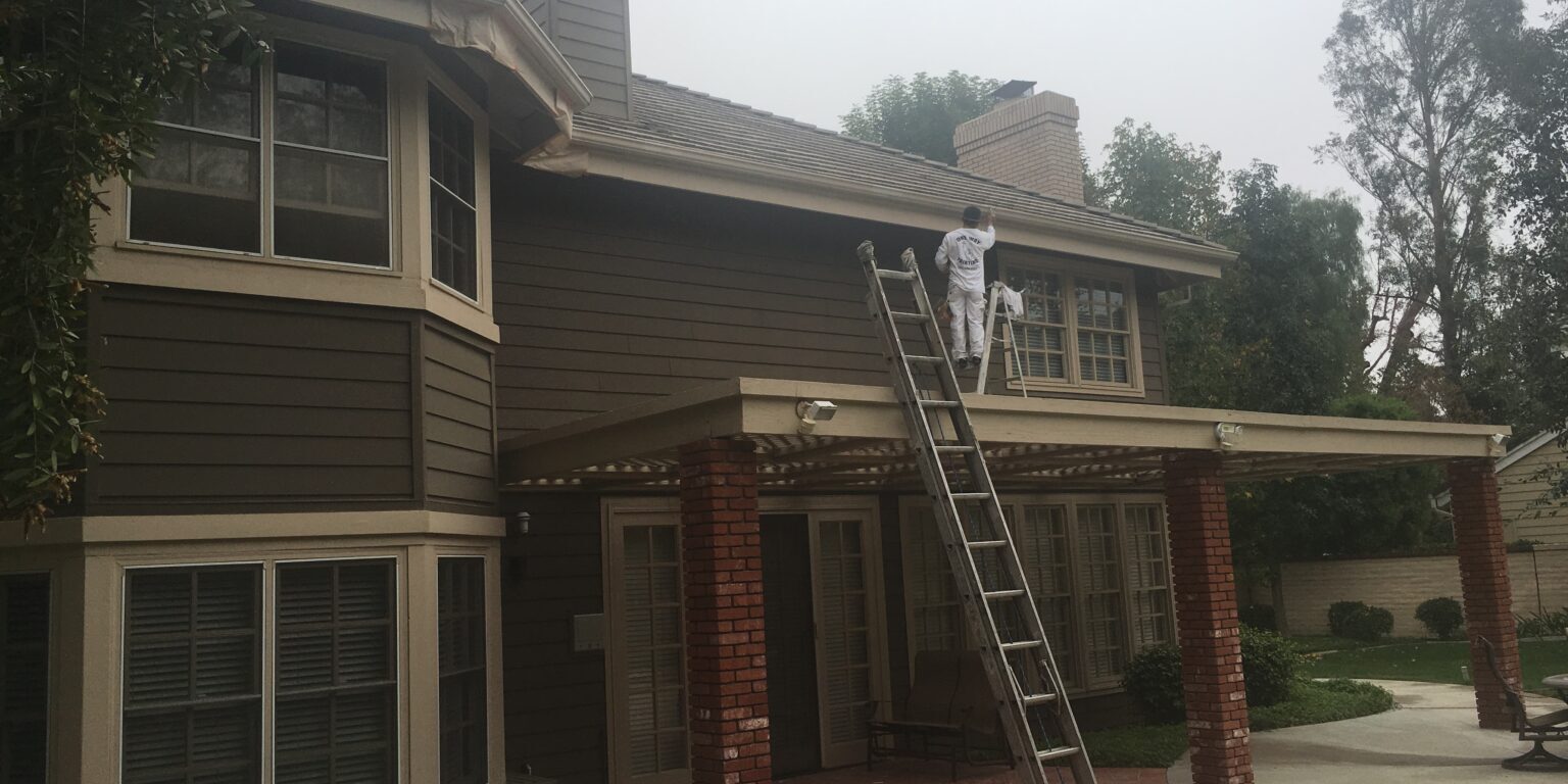 One Way Painting exterior home painter on a ladder while painting a 2-story exterior home in Villa Park, CA.