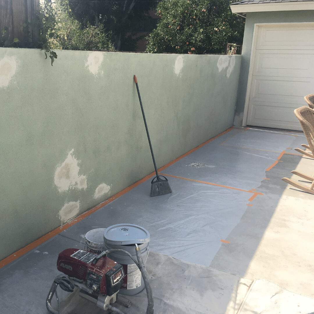 Perimeter stucco wall featuring several spots that have been repaired and primed before painting.