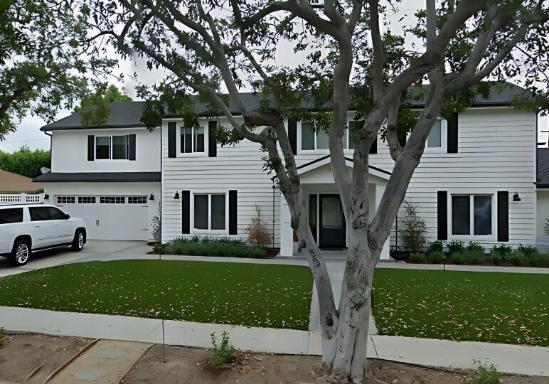 Exterior view of a North Tustin home with fresh white stucco, black shutters, and a beautifully painted garage door, completed by One Way Painting.